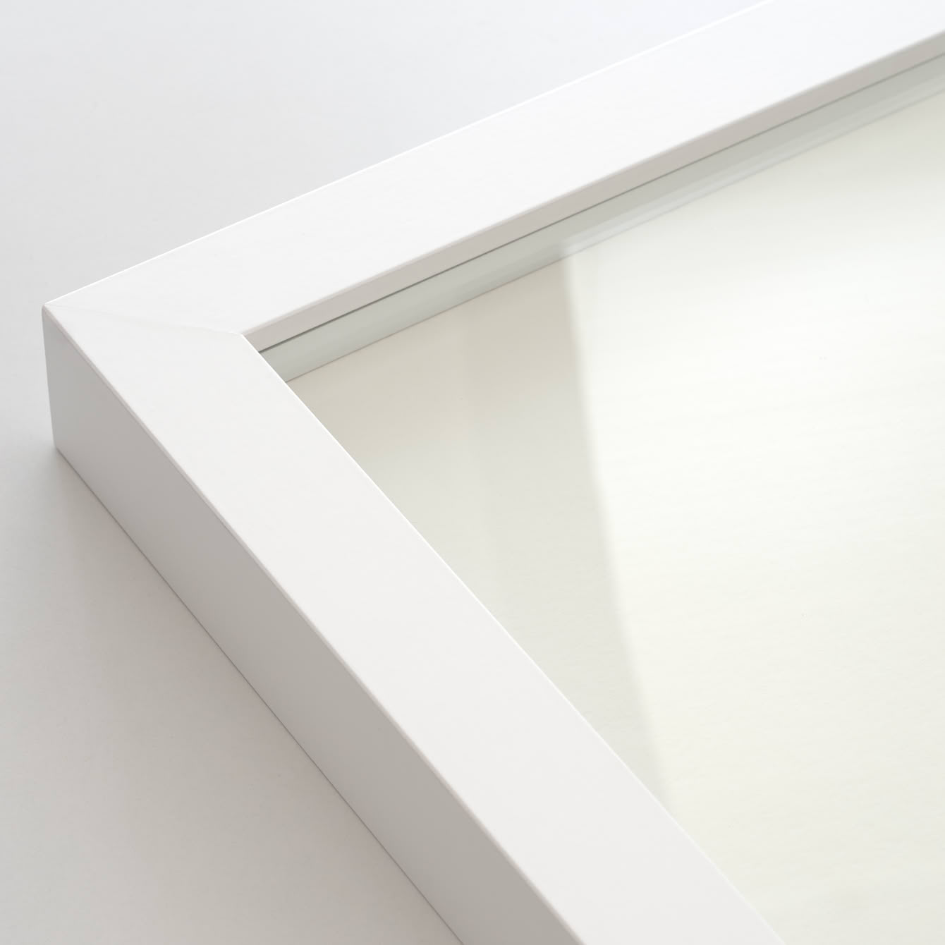 Ecke eines weißen Bilderrahmens mit Normalglas-Scheibe.